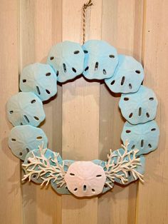 a wreath made out of sand dollarfish and corals on a wooden door frame