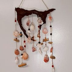 a wall hanging with shells and seashells attached to it's sides on a white wall