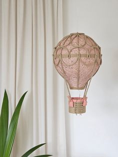 a pink hot air balloon hanging from the ceiling next to a potted palm tree