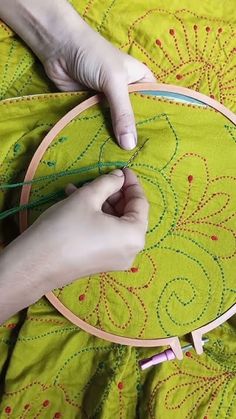 someone is stitching something on a green cloth