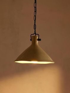 a light that is hanging from a chain in a room with a wall behind it