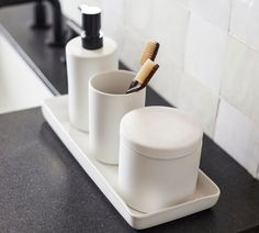 two toothbrushes in cups on a bathroom counter