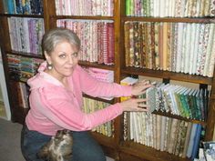 a woman kneeling down in front of a book shelf