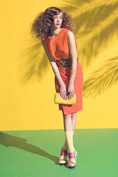 a woman in an orange dress holding a yellow purse