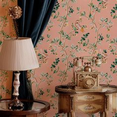 an old fashioned telephone sitting on top of a table next to a lamp and wallpaper