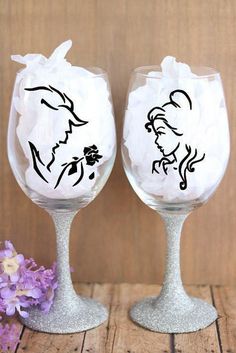 two wine glasses with the silhouettes of beauty and the beast on them, sitting next to each other