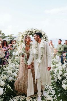 a newly married couple standing in front of a flower covered arch at their wedding ceremony