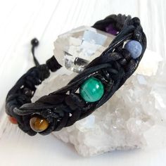 Embrace inner peace and awaken your energy centers with this stunning yoga chakra bracelet. Handcrafted with seven beautiful gemstones, each one carefully selected to resonate with a different chakra point in your body.  About the Bracelet: Materials: 8mm Garnet, Carnelian, Tiger Eye, Sodalite, and Amethyst gemstones, 10mm Malachite gemstone, 6mm Black Agate stoppers, braided waxed cord, leather cord, macrame closure (adjustable) Size: Made to order. Please measure your wrist snugly and add 0.2 inches for a comfortable fit. Style: Unisex, handmade, yoga-inspired This captivating bracelet is perfect for everyday wear, adding a touch of balance and beauty to your life. Each gemstone is meticulously chosen for its believed properties, designed to help harmonize your energy centers, known as c Leather Cord Jewelry, 7 Chakra Bracelet, Bracelet Materials, Buddhist Jewellery, Yoga Chakra, Beautiful Gemstones, Energy Centers, Cord Jewelry, Chakra Jewelry