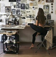 a woman sitting at a desk in front of pictures on the wall