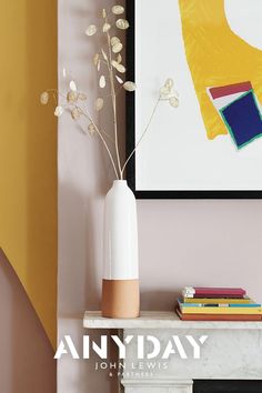 a vase filled with flowers sitting on top of a white table next to a painting