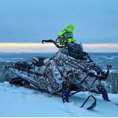 a snowmobile is parked in the snow on top of a snowy hill with trees