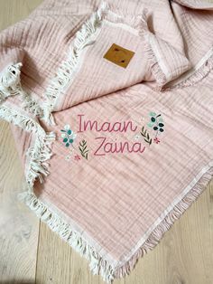 a pink blanket with embroidered name and flowers on the bottom is laying on a wooden floor