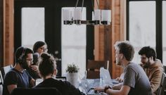 a group of people sitting around a table working on laptops