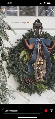 a christmas wreath hanging on the side of a door with pine cones and bells attached to it