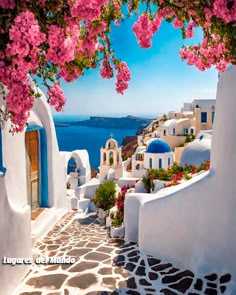 an alley way with flowers and buildings on the cliff overlooking the ocean in oia, greece