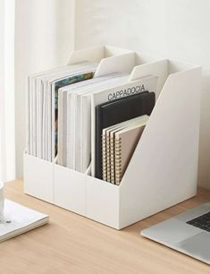 a laptop computer sitting on top of a wooden desk next to a white book holder