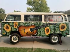 an old van with sunflowers painted on it's side and a guitar in the front