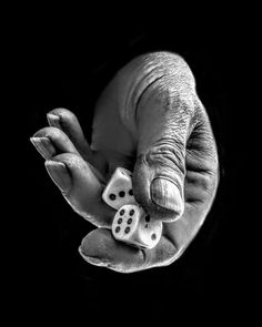 a black and white photo of a hand holding two dice