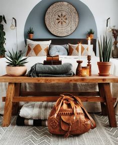 a bed with a wooden bench in front of it and potted plants on the side