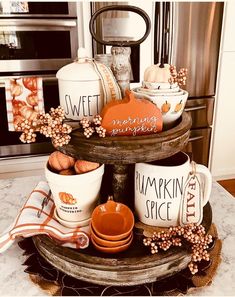 a cake stand with pumpkins and coffee mugs sitting on it's sides