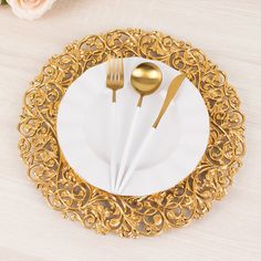 a white plate topped with gold colored utensils and a golden filigreet