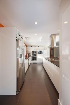 a long kitchen with white cabinets and stainless steel appliances