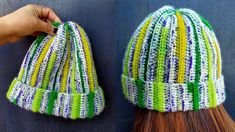 two knitted hats hanging on the side of a blue wall next to a woman's hair