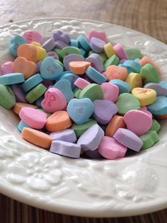 a white bowl filled with candy hearts on top of a table