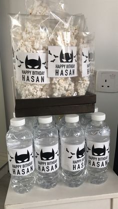 some water bottles are sitting on a table with batman labels and popcorn bags in front of them