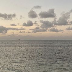 two boats are out on the water at sunset or sunrise in the distance, with some clouds above them