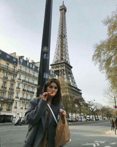 a woman standing in front of the eiffel tower talking on her cell phone