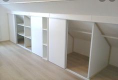 an empty room with white cupboards and shelves