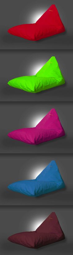 four different colored pillows sitting on top of each other in front of a gray background