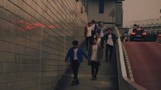 several people walking down a sidewalk next to a wall