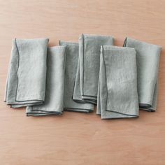 six folded linen napkins sitting on top of a wooden table