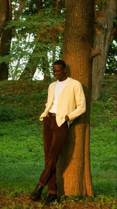 a man leaning against a tree in the grass