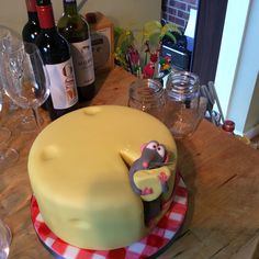 a cake with a monkey on it sitting on a table next to wine bottles and glasses