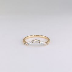 a gold wedding band with three baguettes set in the middle, on a white background