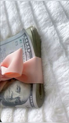 a pink bow on top of one hundred dollar bills