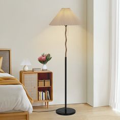 a bedroom with a bed, nightstand and lamp on the floor in front of it