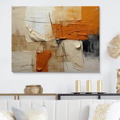 an abstract painting hangs on the wall above a white couch with pillows and gold candles