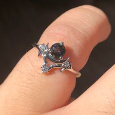 a woman's hand with a ring on it that has a black diamond in the middle