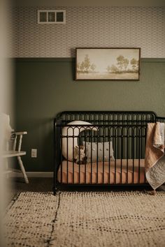 a baby crib in the corner of a room with a painting on the wall