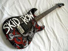 a black and red guitar sitting on top of a white sheet with the words rock city painted on it