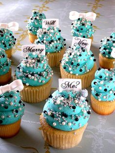 there are many cupcakes with blue frosting and white decorations on top of them