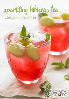 two glasses filled with red drinks sitting on top of a white marble counter next to limes