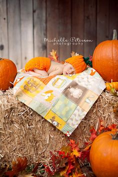 a baby sleeping on top of hay next to pumpkins