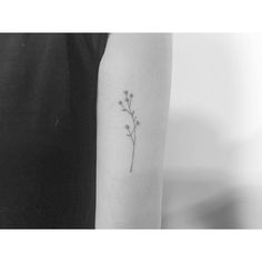 a black and white photo of a flower tattoo on the left upper arm, with small flowers coming out of it