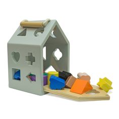 a toy house with wooden blocks and shapes in front of it on a white background