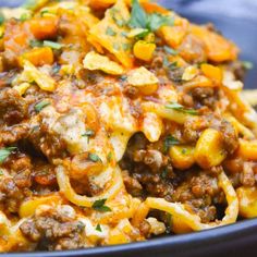 a blue bowl filled with pasta and meat covered in sauce, cheese and parsley